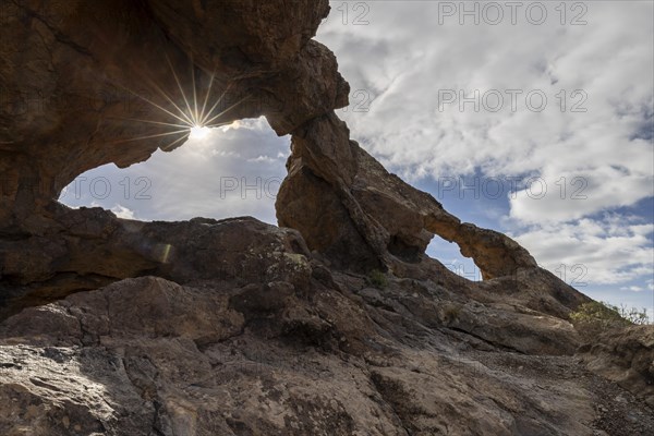 Sun shining through stone arches in volcanic rock
