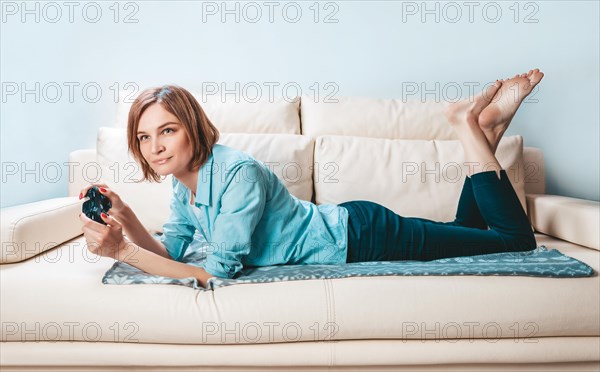 Girl with a joystick in her hands lies on the couch and plays a computer game. ESports concept.