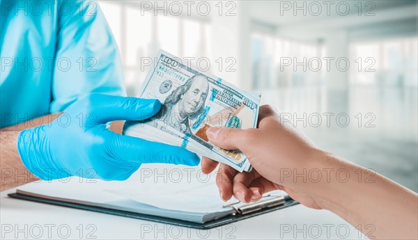 The girl gives the doctor a pack of hundred-dollar bills. Medicine concept.