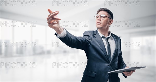 Recruiter in a business suit is standing in the office with a list in his hands. Recruitment concept.