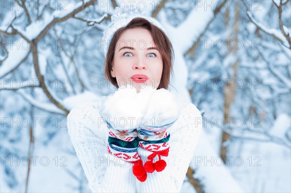 Portrait of a charming girl who blows on the snow. Concept of Christmas