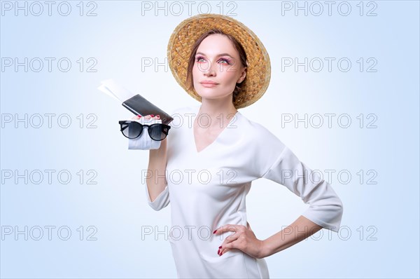 Beautiful girl posing on a white background in a yellow hat. She has a medical mask in her hands. The concept of tourism during the epidemic.