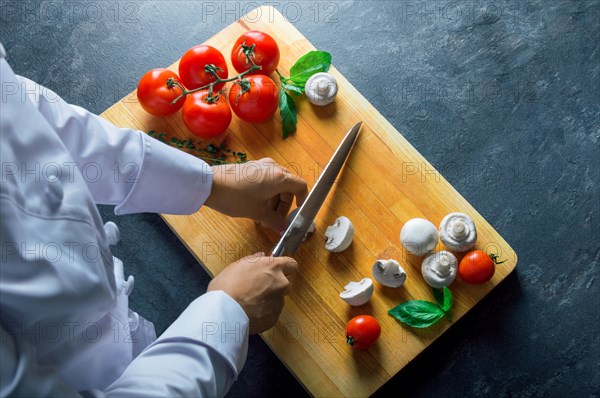 Professional chef cuts vegetables with a sharp knife from Damascus steel.