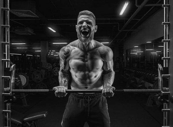 Portrait of an athlete pumping biceps in the gym. Bodybuilding and fitness concept.