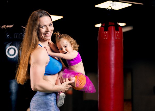 Mom and daughter in their hands posing in the gym.