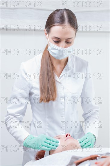 The beautician washes the patient's face before peeling. Skin care concept.