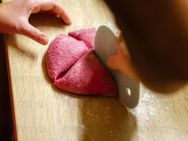 Hand dividing the dough for beetroot burger buns