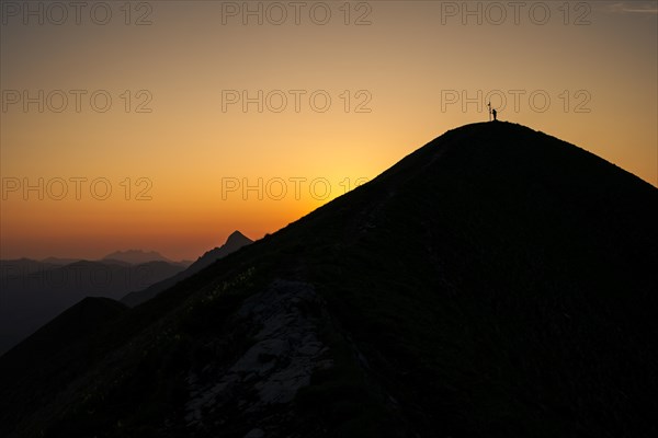 Mountaineer on mountain ridge with Rothorn peak in the background at sunrise