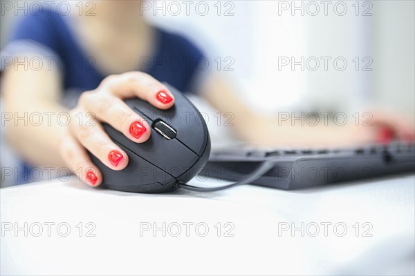 Girl's hand uses a vertical ergonomic joystick of a computer mouse. working at the computer