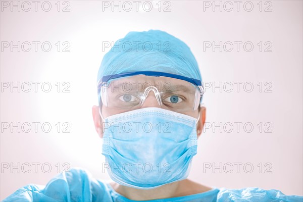 Male surgeon doctor in the operating room looking at the patient at the camera