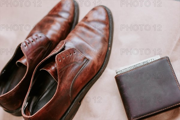 Brown men's shoes made of genuine leather and a brown leather wallet with money