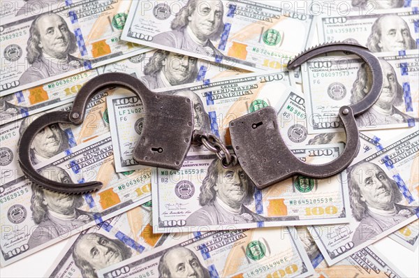 Handcuffs on the background of hundred-dollar bills. Illegal trade. Justice concept.