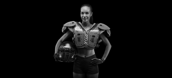 Portrait of a girl in the uniform of an American football team player. Black background. Sports concept.