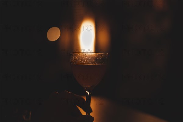 Image of a glass with a cocktail in a night bar against the background of a fiery heater. Restaurant concept