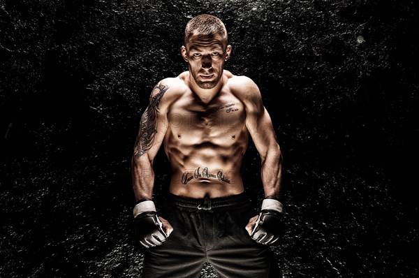 Mixed martial artist posing on a black background. Concept of mma