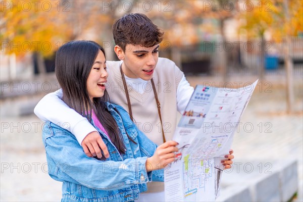 Multi-ethnic young couple looking at a map standing on the city