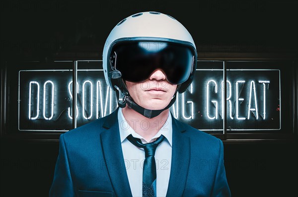 Portrait of a man in a suit and helmet. He stands against a wall with a neon sign. Business concept.