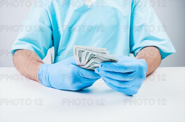 Doctor holds one hundred dollar bills. The concept of corruption in medicine.