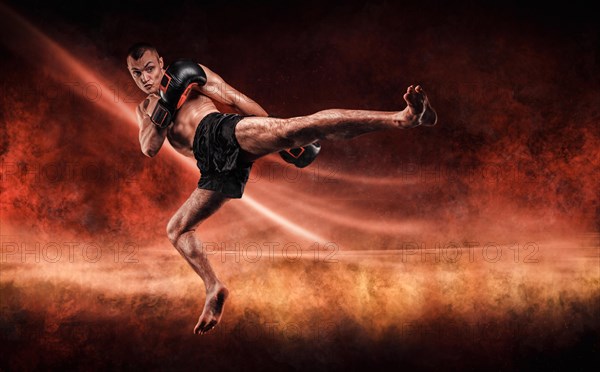 Professional kickboxer jumps with his knee extended. Fiery arena. Mixed martial arts. Sports concept