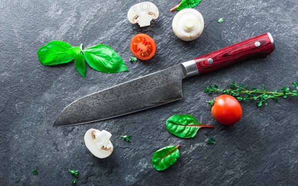 Japanese knife made of Damascus steel lies on a table near the vegetables. View from above