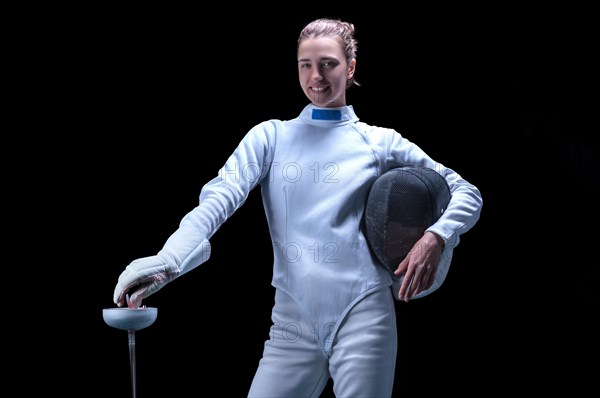 Charming girl dressed as a fencer posing with a mask and a sword. The concept of fencing.