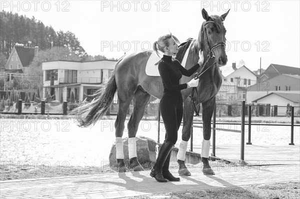 Beautiful stylish woman walking with a horse in a country club. Equestrian sport