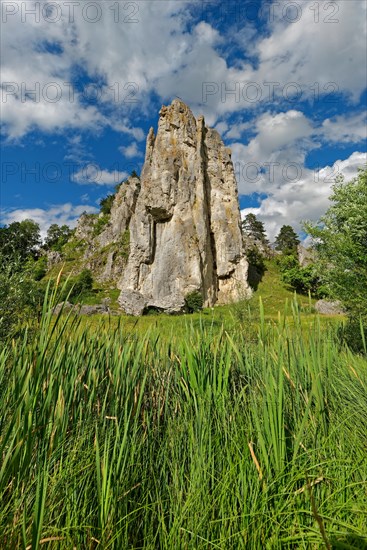 Striking limestone rock formation Burgstein with blue and white sky in the upper Altmuehltal surrounded by green vegetation