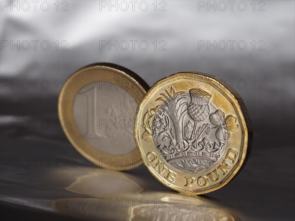 1 pound and 1 euro coin over metal background