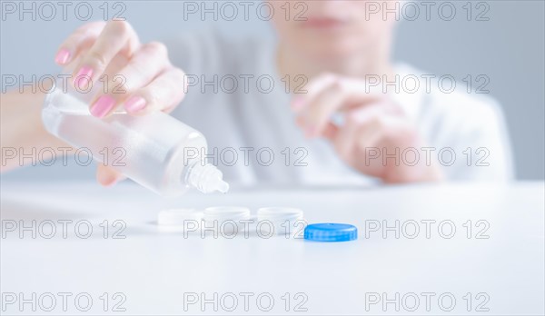 Woman pours liquid for lenses into special boxes. Ophthalmology concept.