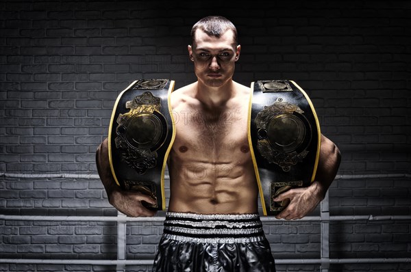 Kickboxing world middleweight champion stands with two belts. The concept of a healthy lifestyle