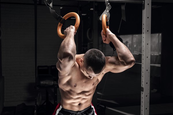 Athlete does warm-up on gymnastic rings. The concept of sport and healthy lifestyle.