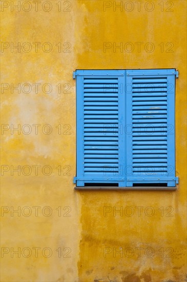 Blue shutter on yellow plaster wall