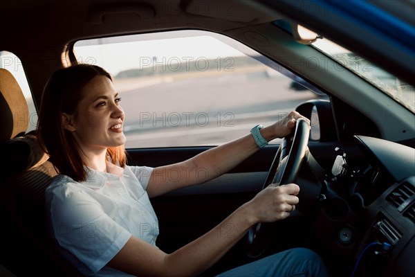 Young beautiful girl taxi driver smiling behind the wheel