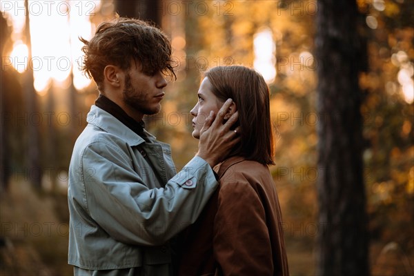 Beautiful fashionable couple in love in the forest at sunset in autumn