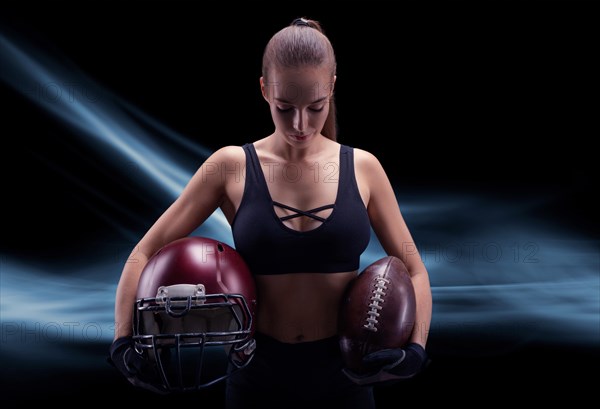 Portrait of a sportive girl in the uniform of an American football team player. Sports concept. Futuristic background.