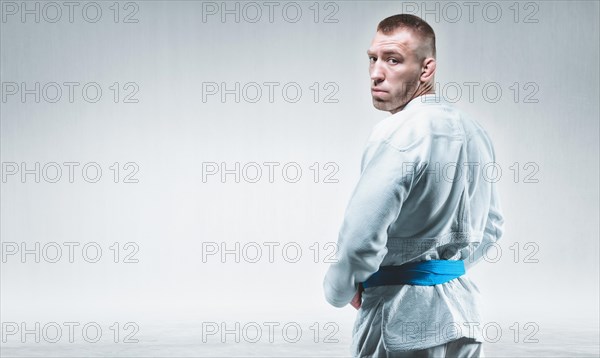 Strong man in a kimono looks over his shoulder. Concept of karate