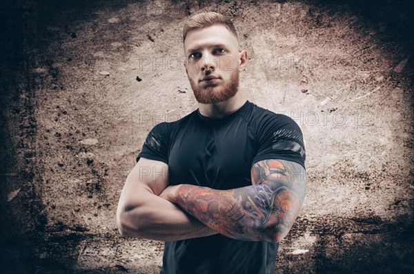 Young muscular guy posing against the background of a concrete wall. Fitness and nutrition concept.