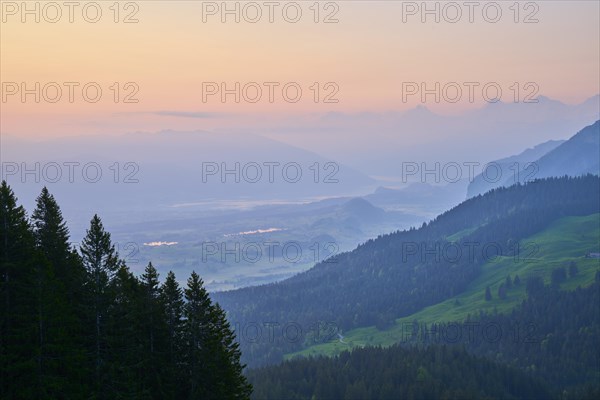 Sunrise over a misty mountain landscape with forest in the foreground
