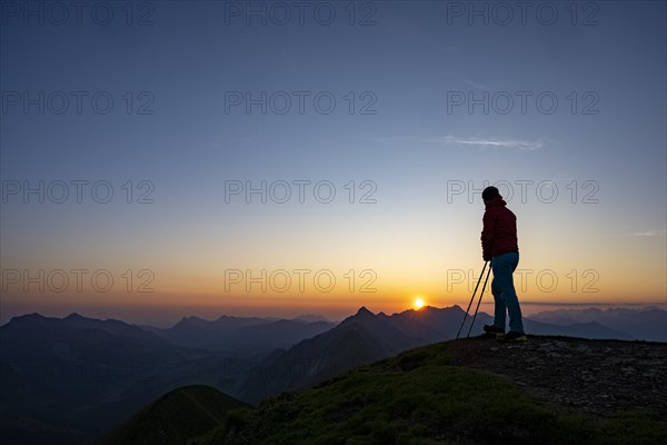 Mountaineer on mountain ridge with Rothorn peak in the background at sunrise