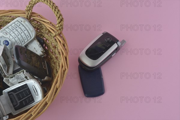 An open flip cell phone in the foreground with more phones in a basket behind