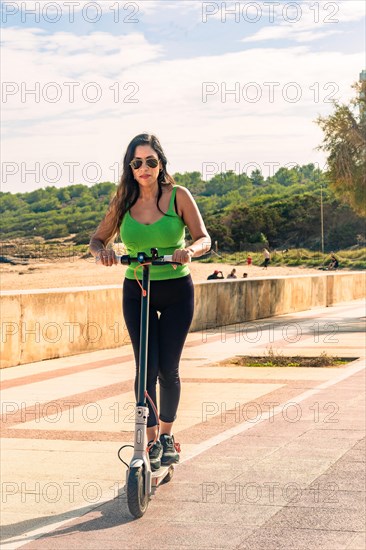 Young latin girl on electric scooters having fun on city street on a sunny summer day. Outdoor portrait girl riding electric scooter in the park