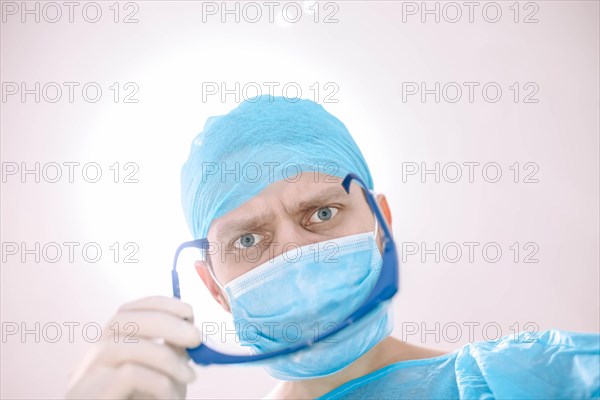 Male surgeon doctor in the operating room looking at the patient at the camera