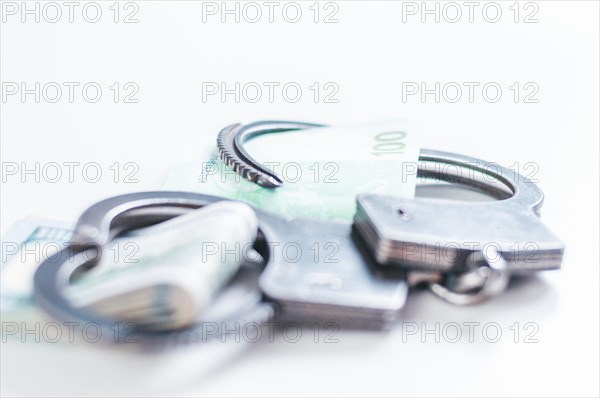 Packs of euros and hundred dollar bills are enclosed in handcuff bracelets. The concept of theft