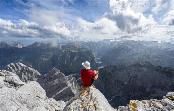 Mountaineer sitting on a rock on the summit of the Watzmann Mittelspitze