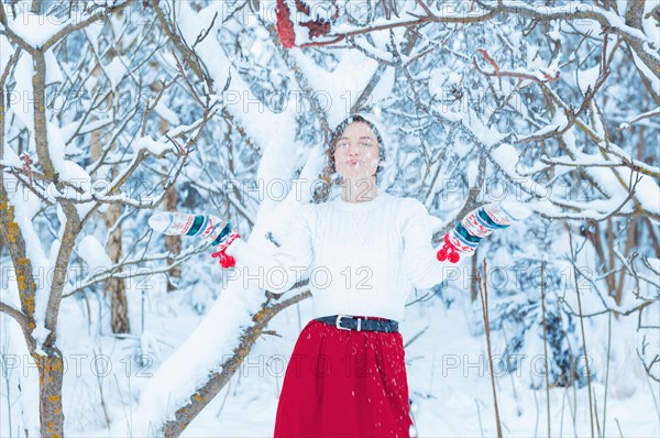 Portrait of a charming girl who stands under a snowy tree. Concept of Christmas