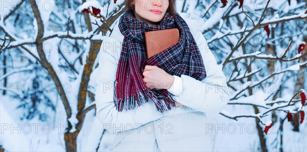 Portrait of a charming girl who reads a book in the winter forest. Concept of Christmas