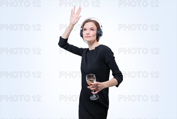Portrait of a woman in professional headphones with a glass of wine in her hand. White background. Dj concept.