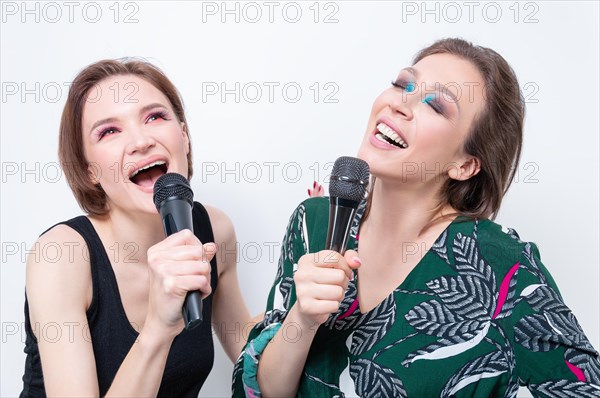 Portrait of two girls with microphones in their hands. Karaoke concept.