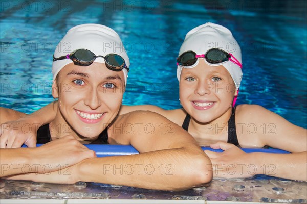 Charming coach with his student swimming in the pool and smiling