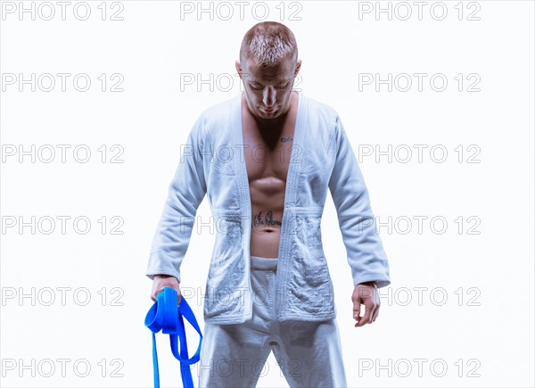 Athlete in a kimono with a blue belt stands with his head down. The concept of karate and judo.